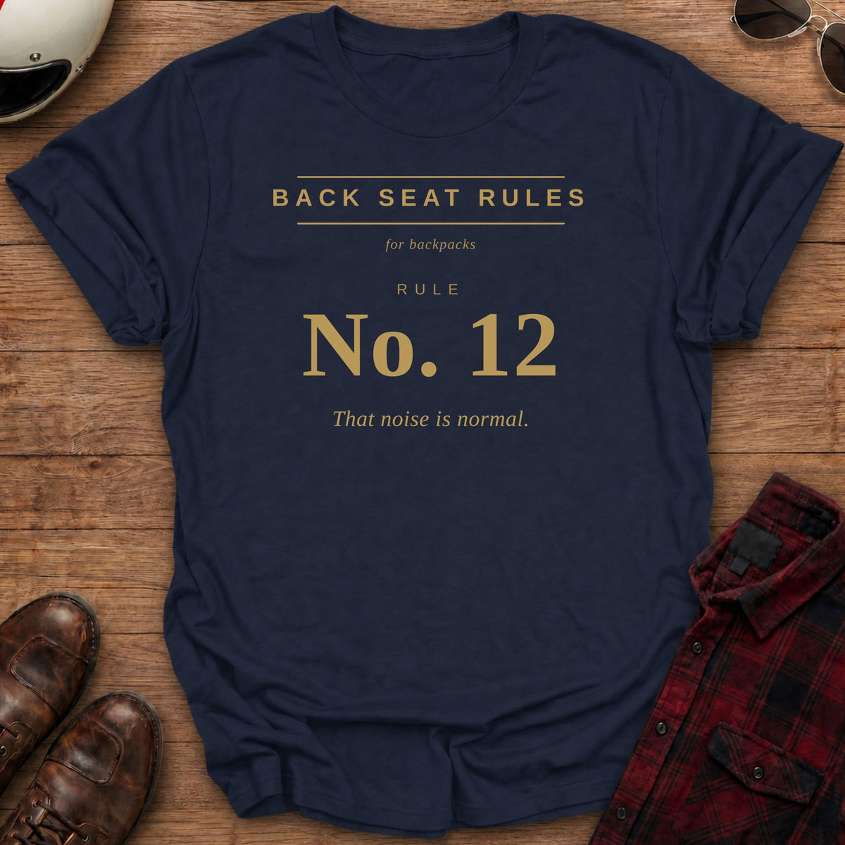 Navy t-shirt with gold type on the front reading Back Seat Rules, for backpacks, Rule No. 12: That noise is normal.