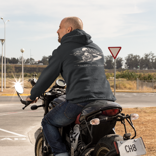 Man riding a motorcycle on a road with a clear sky