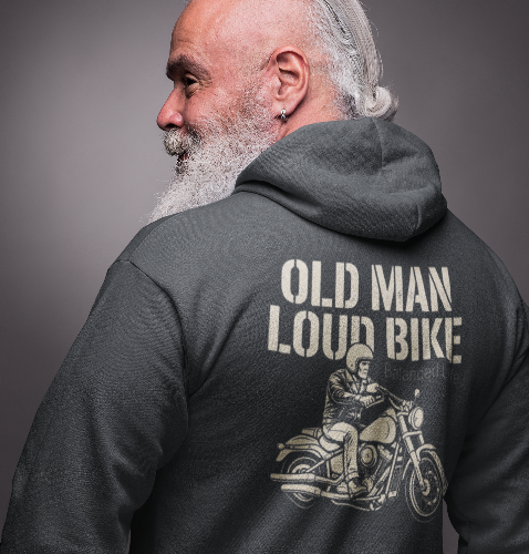A man with a white beard and hair tied back, wearing a dark gray hoodie from the back. The hoodie features a large graphic print on the back with the text 'OLD MAN LOUD BIKE' and an illustration of a man riding a cruiser motorcycle.