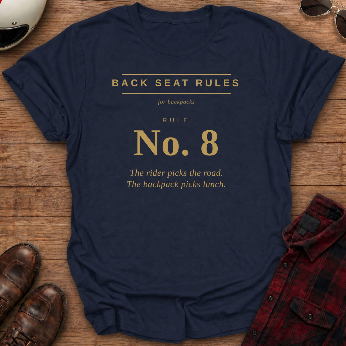 Navy t-shirt with gold type on the front reading Back Seat Rules, for backpacks, Rule No. 8: The rider picks the road. The backpack picks lunch.