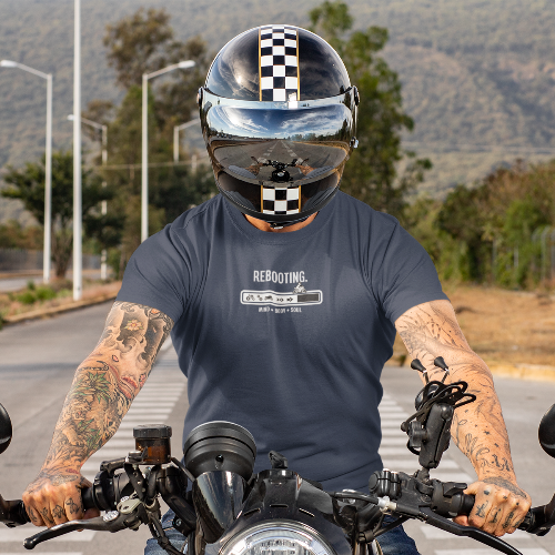 Person on a motorcycle wearing a helmet with a checkered pattern, sitting on a road.